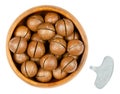 Macadamia nuts with sawn nutshells, in wooden bowl with opener key