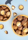 Macadamia nuts in shell in wood bowl with broken macadamia on blue background Royalty Free Stock Photo
