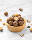Macadamia nuts with shell in wood bowl with broken macadamia on marble table background Royalty Free Stock Photo