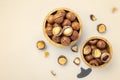 Macadamia nuts in shell in wood bowls with broken macadamia on beige background, top view Royalty Free Stock Photo