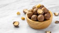 Macadamia nuts in wood bowl with broken macadamia on marble table background, closeup Royalty Free Stock Photo