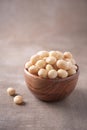 Macadamia nuts in wooden bowl on wood textured background. Copy space. Superfood, vegan, vegetarian food concept. Macro of Royalty Free Stock Photo