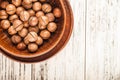 Macadamia nuts on a wooden plate on a white textural table closeup and copy space Royalty Free Stock Photo