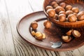 Macadamia nuts on a wooden plate on a white textural table closeup and copy space Royalty Free Stock Photo