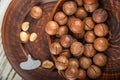 Macadamia nuts on a wooden plate on a white textural table closeup and copy space Royalty Free Stock Photo