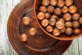 Macadamia nuts on a wooden plate on a white textural table closeup and copy space Royalty Free Stock Photo