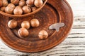 Macadamia nuts on a wooden plate on a white textural table closeup and copy space Royalty Free Stock Photo