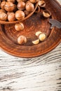 Macadamia nuts on a wooden plate on a white textural table closeup and copy space Royalty Free Stock Photo