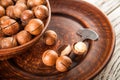 Macadamia nuts on a wooden plate on a white textural table closeup and copy space Royalty Free Stock Photo