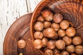 Macadamia nuts on a wooden plate on a white textural table closeup and copy space Royalty Free Stock Photo