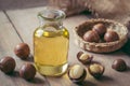 Macadamia oil in bottle and macadamia nuts on wooden table