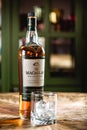 The Macallan whiskey bottle and glass with ice cubes on wooden t