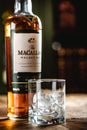 The Macallan whiskey bottle and glass with ice cubes on wooden t