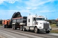 Macamic, Quebec, Canada, 2023-08-21 : Planing machine removing asphalt from a road and transferring it to a semi-trailer truck