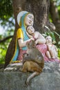Macaque monkey with a baby next to a statue of the Madonna and Children in Rishikesh, India