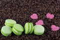 Macaron mint green biscuits on arabica grains and pink hearts Royalty Free Stock Photo