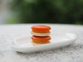 Macaron orange color in white plate shape ellipse, Dessert snacks Afternoon on marble table