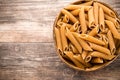Macaroni on the bowl, wooden background. Royalty Free Stock Photo