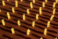 Macaroni in the form of yellow spirals on a brown background lined up and stand
