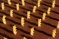 Macaroni in the form of yellow spirals on a brown background lined up and stand