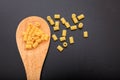 Macaroni pasta in a ladle, black background Royalty Free Stock Photo