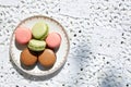 Macarons cookies in pink, green and brown colors with ceramic saucer