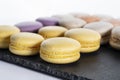 Macarons are laid out on a black slate in beautifully colored rows. Royalty Free Stock Photo