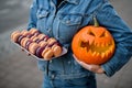 macarons on tray and pumpkin carved with scary laughing face in the hands of woman Royalty Free Stock Photo