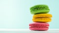 Macaroon cake red and yellow and green on a white wooden table on a blue background Royalty Free Stock Photo