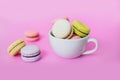 Macaroon or macaron biscuits in mug on pink background.