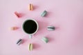 Macaroons around coffee cup on a pink background. Flatlay