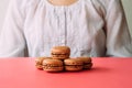 Macaroons on heap on pink table against woman