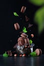 Macaroons with nuts and pieces of chocolate fall into a vintage vase.Photo on a black background. Copy of the space. Vertical