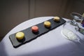 Macaroons on a slate board with a water glass on a table with a white tablecloth Royalty Free Stock Photo