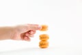 Macaroons on a white background and hand holding one and folding them into a tower, colorful macaroons, selective focus