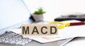 MACD - Moving Average Convergence Divergence Wooden cubes with letters on a laptop keyboardwith charts , magnifier