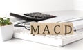 MACD - Moving Average Convergence Divergence written on a wooden cube on keyboard with office tools