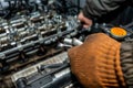 Machanic repairman at the cylinder head servicing. Disassembled motor