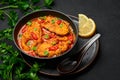 Macher Jhol in black bowl on dark slate table top. Indian cuisine Bengali Fish Curry. Asian food and meal Royalty Free Stock Photo