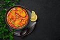 Macher Jhol in black bowl on dark slate table top. Indian cuisine Bengali Fish Curry. Asian food and meal Royalty Free Stock Photo