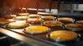 a machine in a bakery production line, filling fluffy, golden brown doughnuts with shiny, syrupy caramel