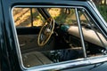 Machine black, inside the seat of beige leather, retro car.stage in summer.driver`s seat, white steering wheel.view from an open