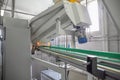 Machine for blowing plastic bottles from PET preforms, industrial conveyor belt in factory interior