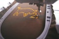 Machine head and working area of embroidery machine stitching ox symbol and number 21 with golden yarn on shiny olive fabric