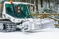 Machine snowcat compacts the snow on the ski slopes in coniferous forest,