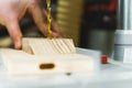 Machine tool in carpenter wood workshop. Closeup shot of drill bit drilling a hole in light wooden piece. Unrecognizable Royalty Free Stock Photo