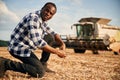 Machinery behind. Beautiful African American man is in the agricultural field Royalty Free Stock Photo