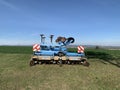 Machinery, equipment for plowing the ground, blue soil stands on green grass against the background of a blue sky. Close-up. Royalty Free Stock Photo