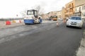 Machines performing asphalting and paving work on a city road.