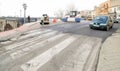 Machines performing asphalting and paving work on a city road.